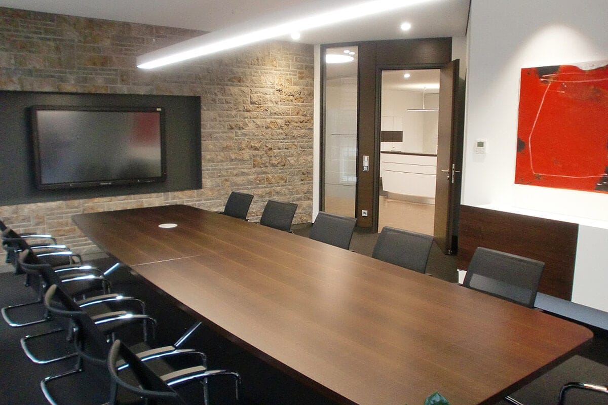 Konferenzraum mit langem Holztisch und Natursteinwand im Finanzinstitut