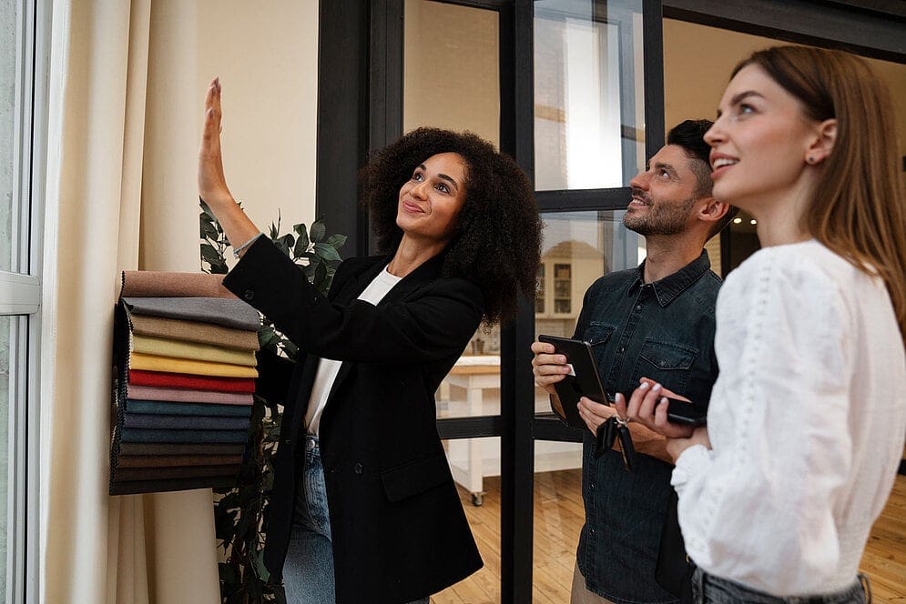 Homestylistin zeigt Kunden Stoffmuster im Showroom