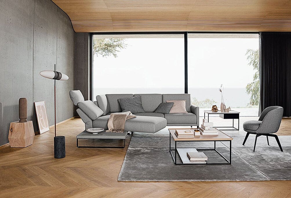 Graues Sofa von Rolf Benz in einem Wohnraum mit Holzdecke