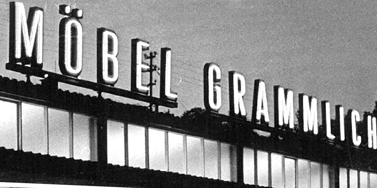 Historische Nachtaufnahme des Möbelhauses mit leuchtendem Schriftzug Möbel Grammlich